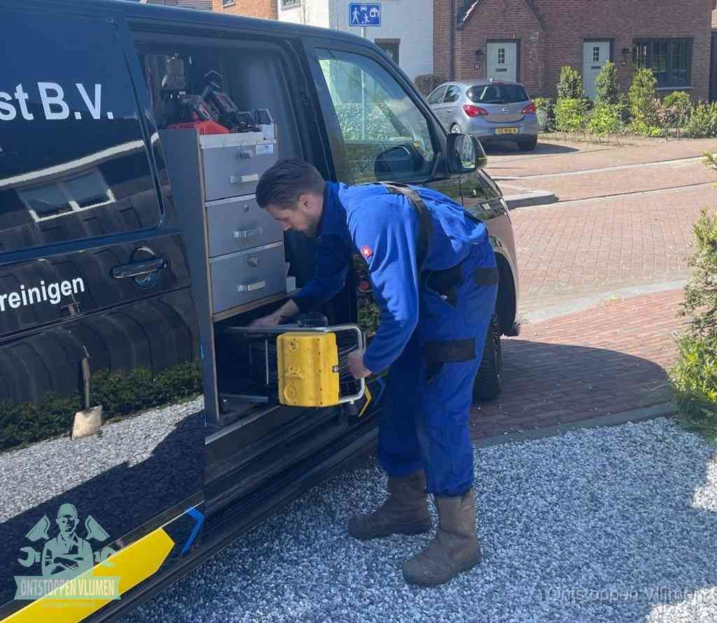 Een monteur pakt apparatuur uit de bedrijfsbus voor service aan huis, het moment om een professional in te schakelen voor een verstopte wc in Vlijmen