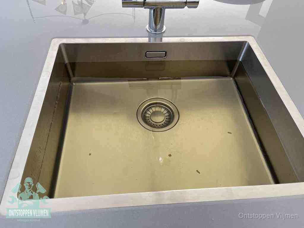 Stilstaand water in een rvs spoelbak dat niet wegloopt, een duidelijk signaal van een gootsteenverstopping in Vlijmen