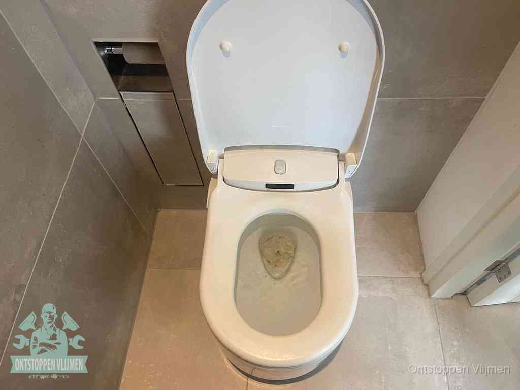 Een wit hangtoilet waarin een prop wc-papier op het water blijft drijven, een duidelijk signaal van een verstopte wc in Vlijmen