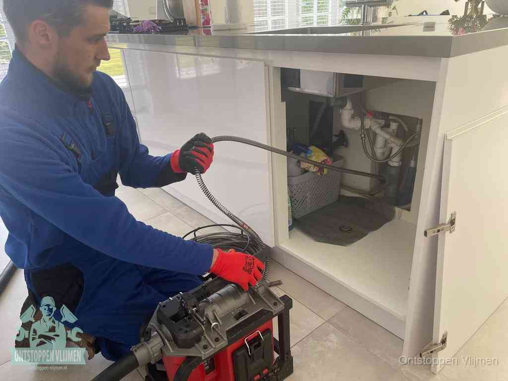 Een monteur reinigt de keukenafvoer grondig met een veermachine om terugkerende gootsteenverstoppingen te voorkomen in Vlijmen