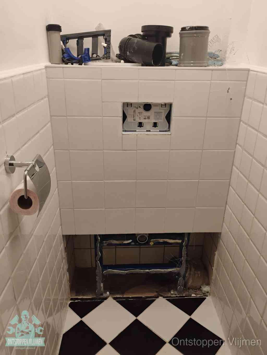 Een toiletruimte waar het hangtoilet en de inbouwreservoir-onderdelen zijn vrijgelegd voor onderhoud, periodiek nazicht voorkomt een wc-verstopping in Vlijmen