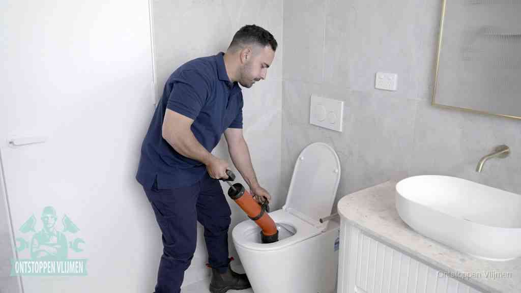 Een monteur gebruikt een handmatige perspomp (toiletontstopper) op een wandcloset tijdens het professioneel wc ontstoppen in Vlijmen