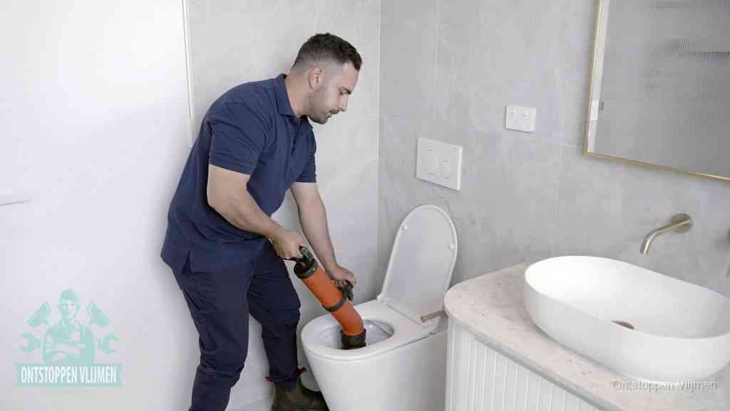Een man gebruikt een handmatige luchtdruk-ontstopper in een modern betegeld toilet om zelf de wc te ontstoppen in Vlijmen